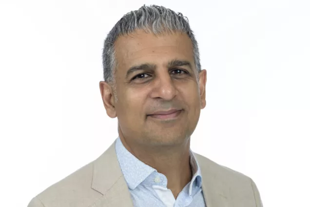 Image of Ramin Massoumi with a beige suit, blue shirt and white background.